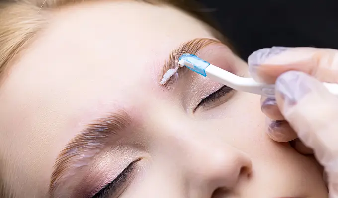 Нанесение фиксирующего состава на волоски при долговременной укладке и ламинировании бровей